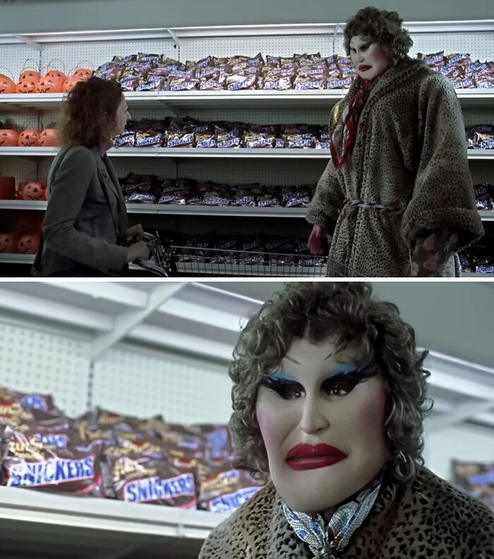 Person in creepy mask and heavy makeup wearing a leopard coat in a store aisle filled with candy bars, creating eerie vibes.