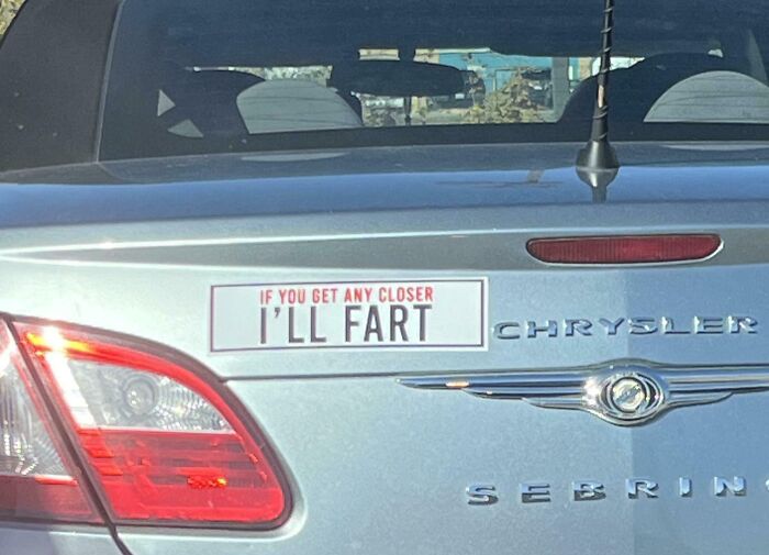 Silver Chrysler Sebring with a humorous bumper sticker that reads If you get any closer I'll fart, showcasing clever bumper stickers.