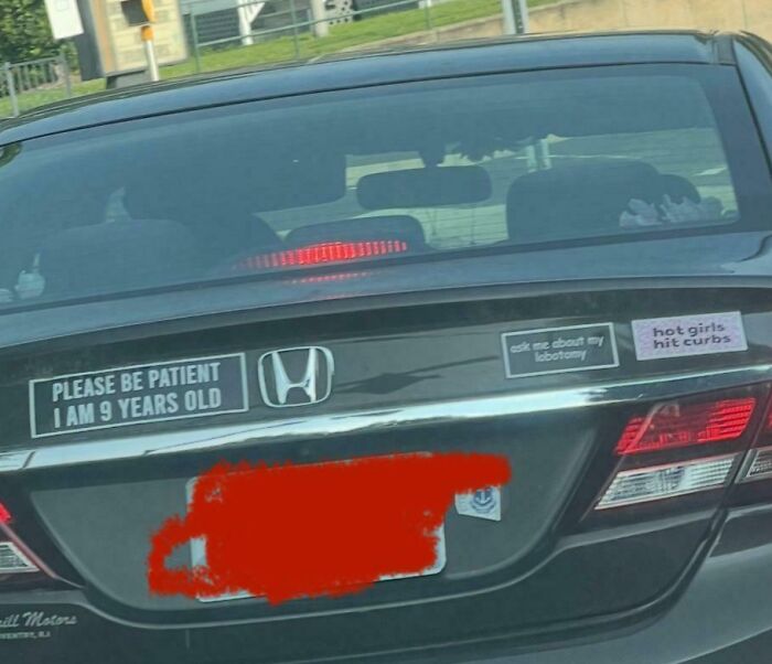 Black Honda car with funny bumper stickers including a child patience request and humorous sayings on the road.