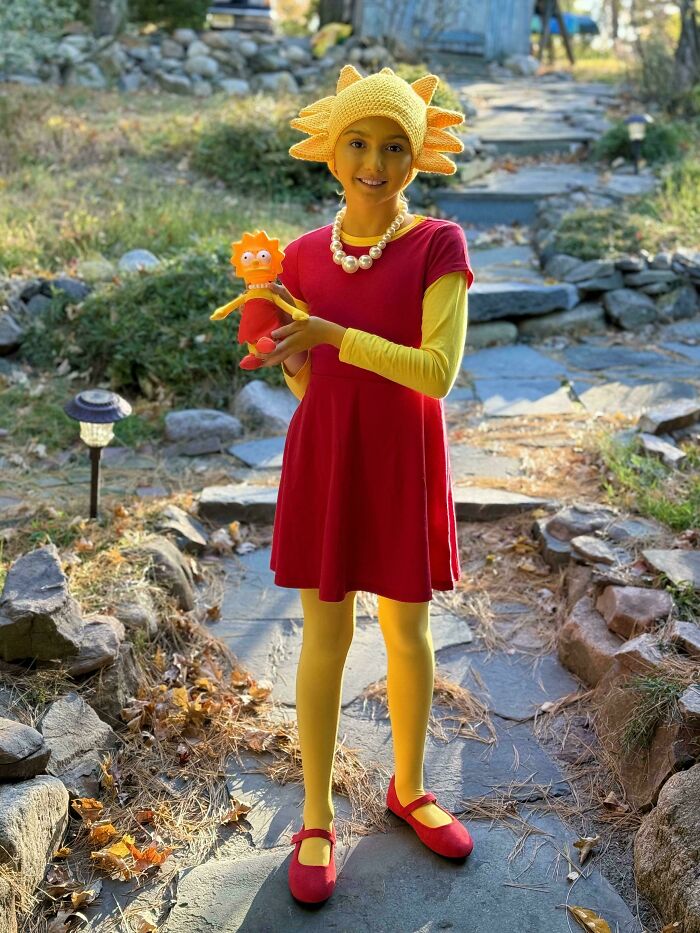 Child in a creative Halloween costume holding a matching doll, showcasing amazing kids' Halloween costume ideas outdoors.