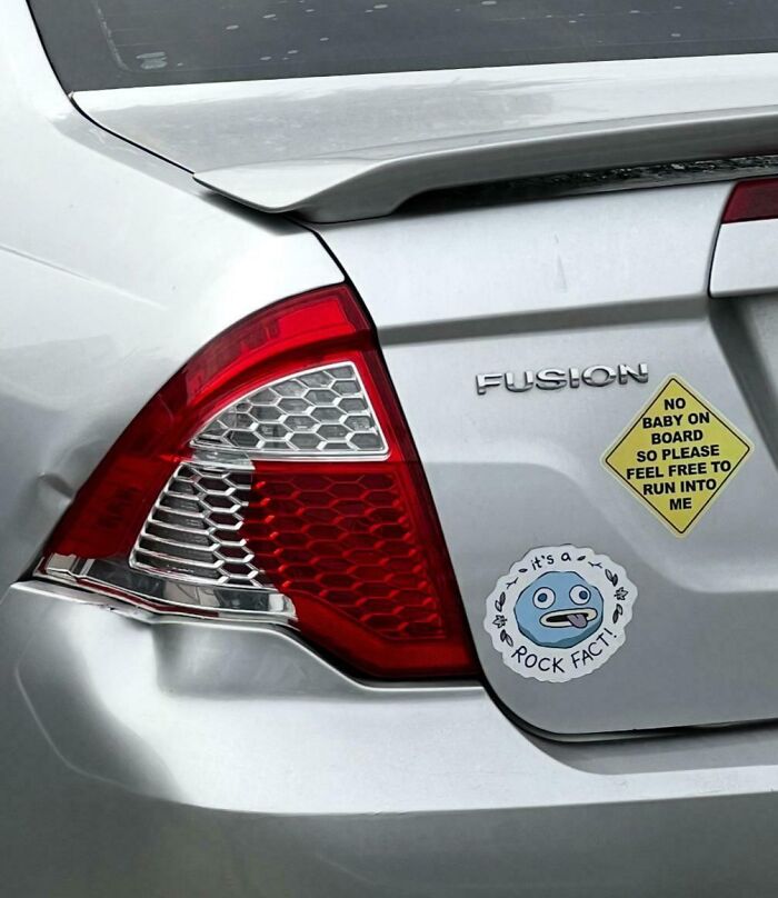 Rear of silver Fusion car with clever and hilarious bumper stickers, including a sarcastic warning and a funny cartoon rock fact.