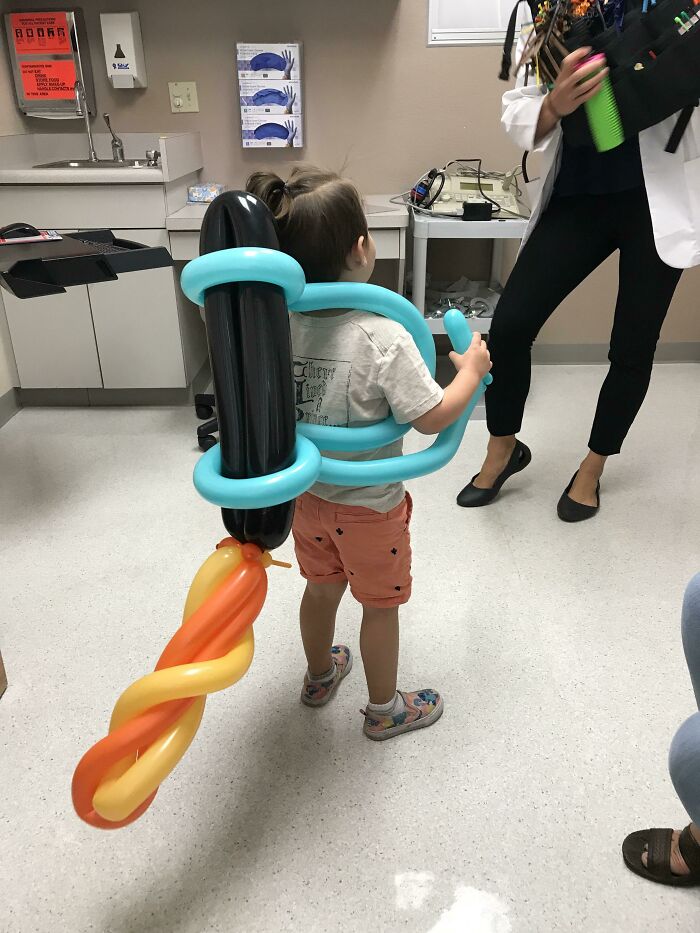 Child wearing a colorful balloon sword at a doctor's office, showing hilarious and wholesome things doctors did to ease patients.