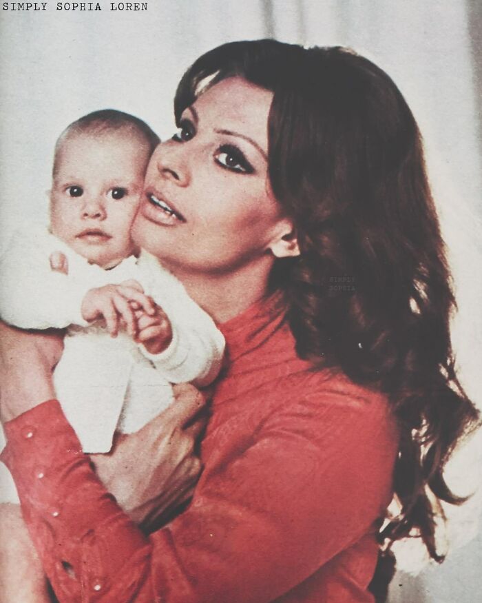 Sophia Loren holding a baby, showcasing the iconic Italian beauty and Hollywood legend in a classic portrait pose.