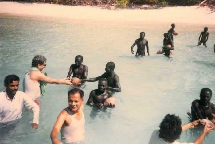 Group of people in shallow water sharing coconuts, capturing fascinating moments that help see the world differently.