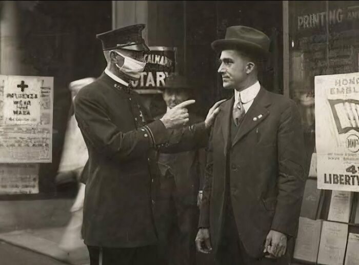 Vintage photo showing a police officer wearing a mask talking to a man in a suit, illustrating fascinating photos and stories.