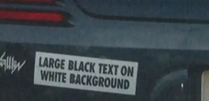 Car bumper with a clever and hilarious bumper sticker featuring large black text on a white background snapped on the road.
