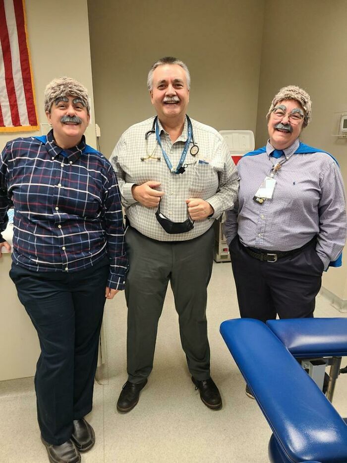 Three doctors in a clinic dressed humorously with wigs and fake mustaches to put patients at ease.