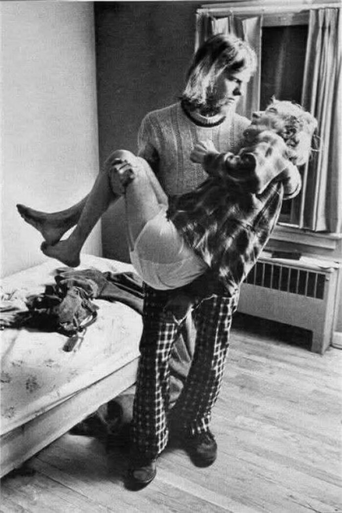 Man showing the good in this world by gently carrying an elderly woman in a cozy room with natural light.