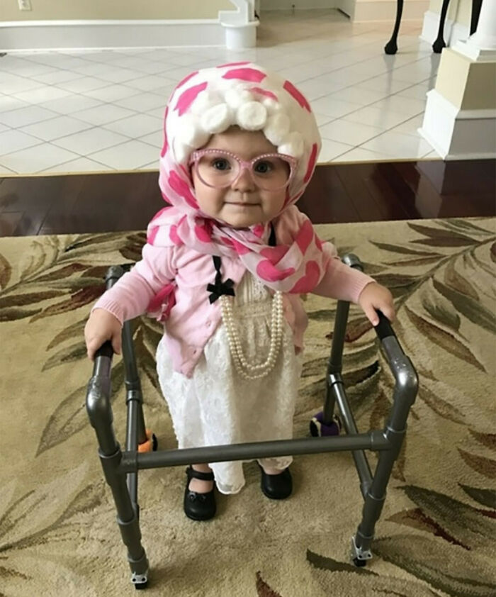 Toddler in a cute vintage-inspired Halloween costume with glasses, scarf, pearls, and walker for kids Halloween costume ideas.