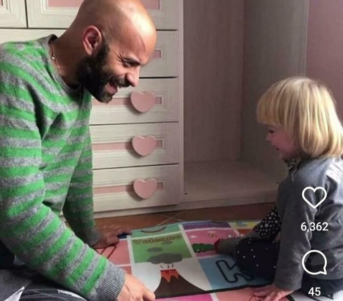 Man and child smiling together while playing on colorful mat, highlighting men are good moments of kindness.