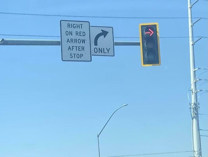 Confusing road signs showing right on red arrow after stop with a red right-turn traffic light against a clear blue sky.