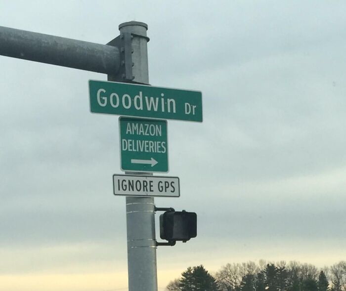 Road sign on Goodwin Drive showing Amazon delivery direction with additional sign instructing to ignore GPS.