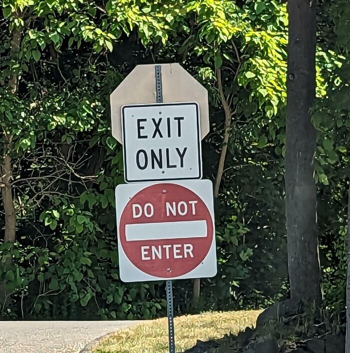 Confusing road signs showing exit only and do not enter on the same post causing driver uncertainty and GPS navigation issues.