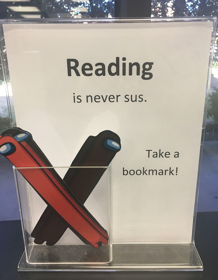 Sign saying reading is never sus with bookmarks shaped like characters, captured in a weird and blessed cursed pic.