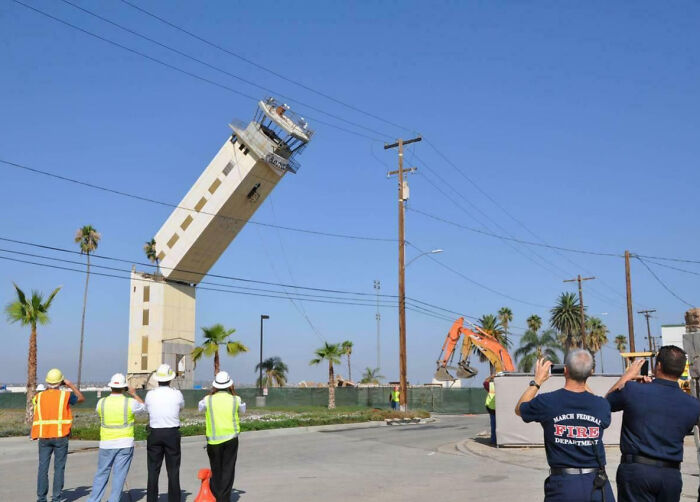 A leaning tower captured in a weird, blessed, and cursed moment with people watching and taking photos.