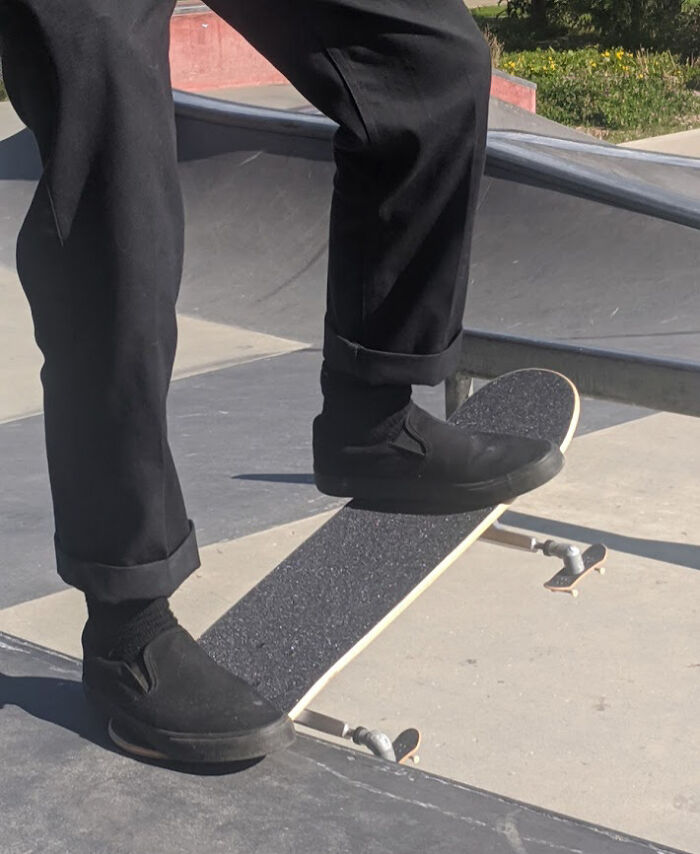 Person wearing black pants and shoes performing a skateboarding trick in a skatepark with weird and cursed vibes.