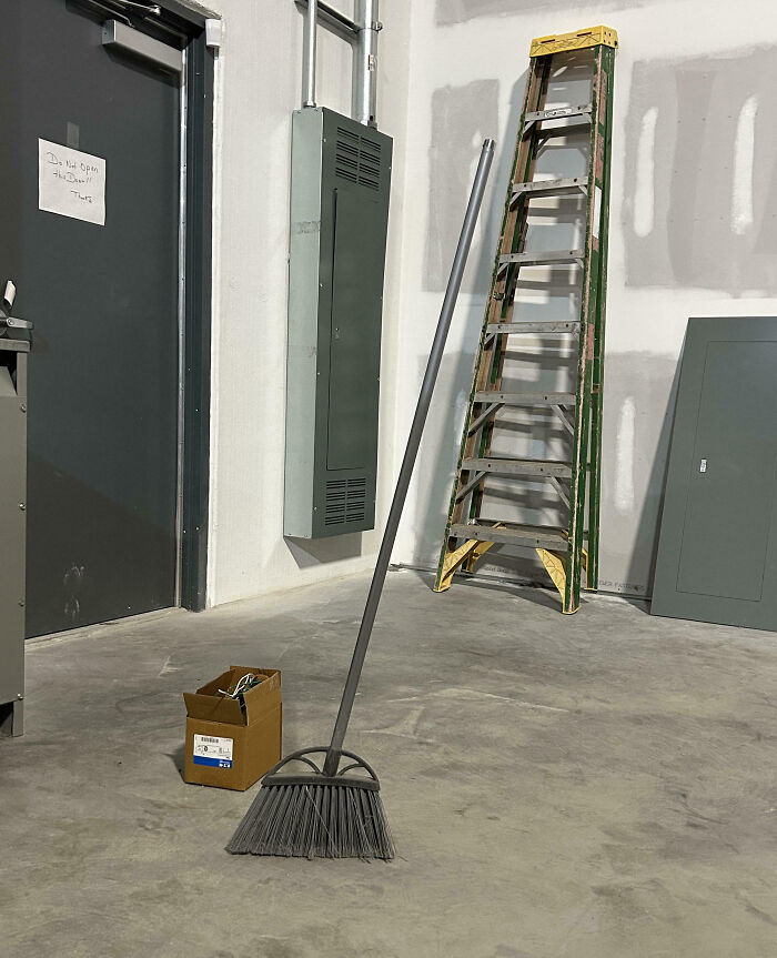 Unphotoshopped photo of a broom seemingly standing on its own in a room with ladder and electrical panels.