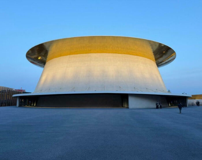 Futuristic building with rounded, UFO-like shape and smooth surface under clear blue sky in unphotoshopped real photo.