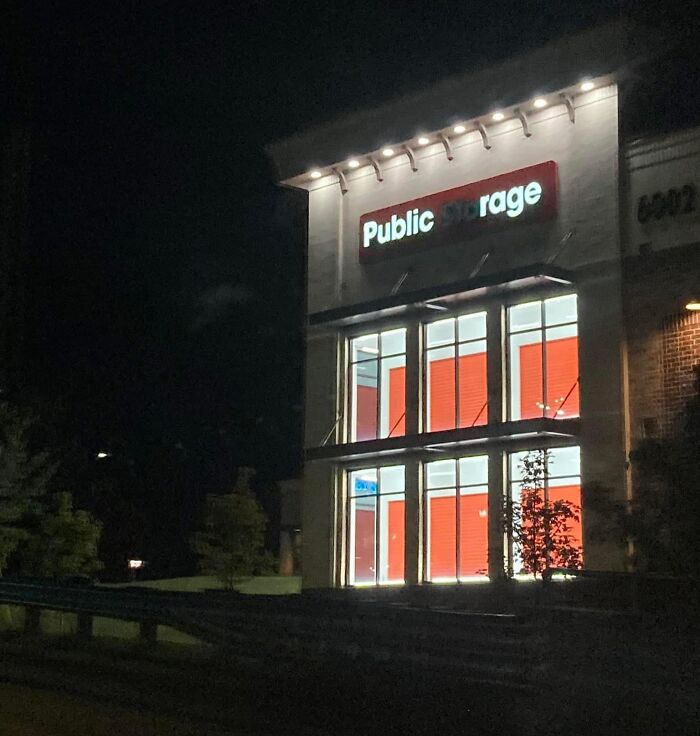 Night view of a public storage facility with bright orange doors contrasted against darkness in a humorous out of context setting.