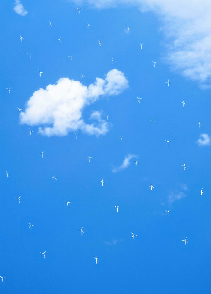 Wind turbines appearing to float in the sky among clouds in an unphotoshopped pic that looks fake but is real.