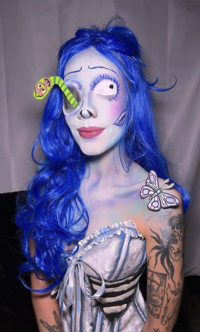 Woman with creative Halloween costume makeup, blue wig, and butterfly detail, showcasing unique Halloween costume ideas.