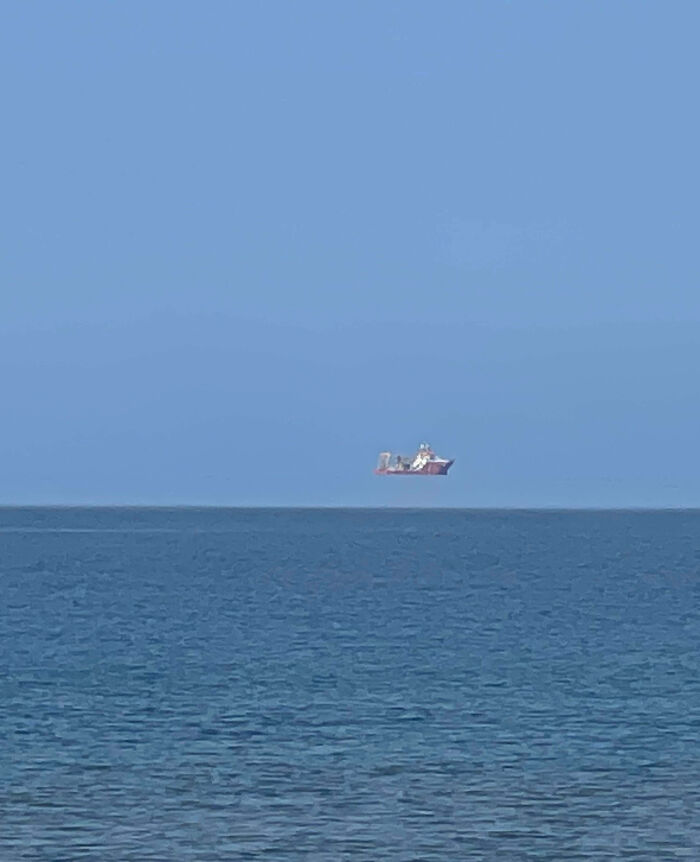Ship appears to be floating above water due to an unphotoshopped optical illusion that looks fake but is real.