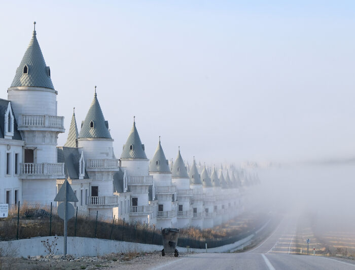 A row of unphotoshopped houses with pointed roofs disappearing into dense fog, looking unreal but 100 percent real.