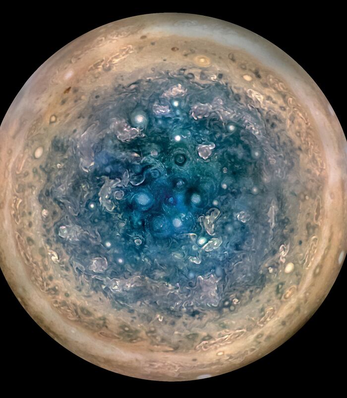 Close-up epic astronomy photo showing swirling blue and beige storms on the mysterious surface of a gas giant planet.