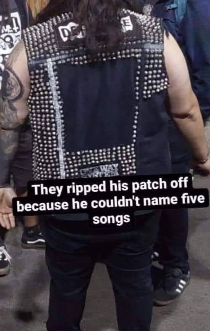 Person wearing a studded vest with ripped patches, captured in a humorous out of context pleasures of the occult moment.
