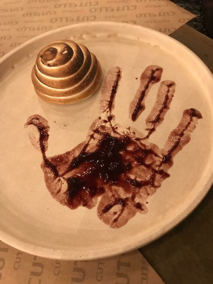 Plate with a dessert and a handprint made from a sauce, illustrating cursed and disgusting pictures of food that might make you eeeeew