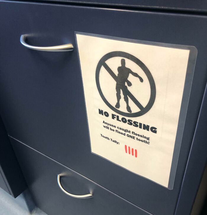 No flossing sign on dark blue cabinet with humorous warning and tooth tally in a doctor’s office for patient comfort.