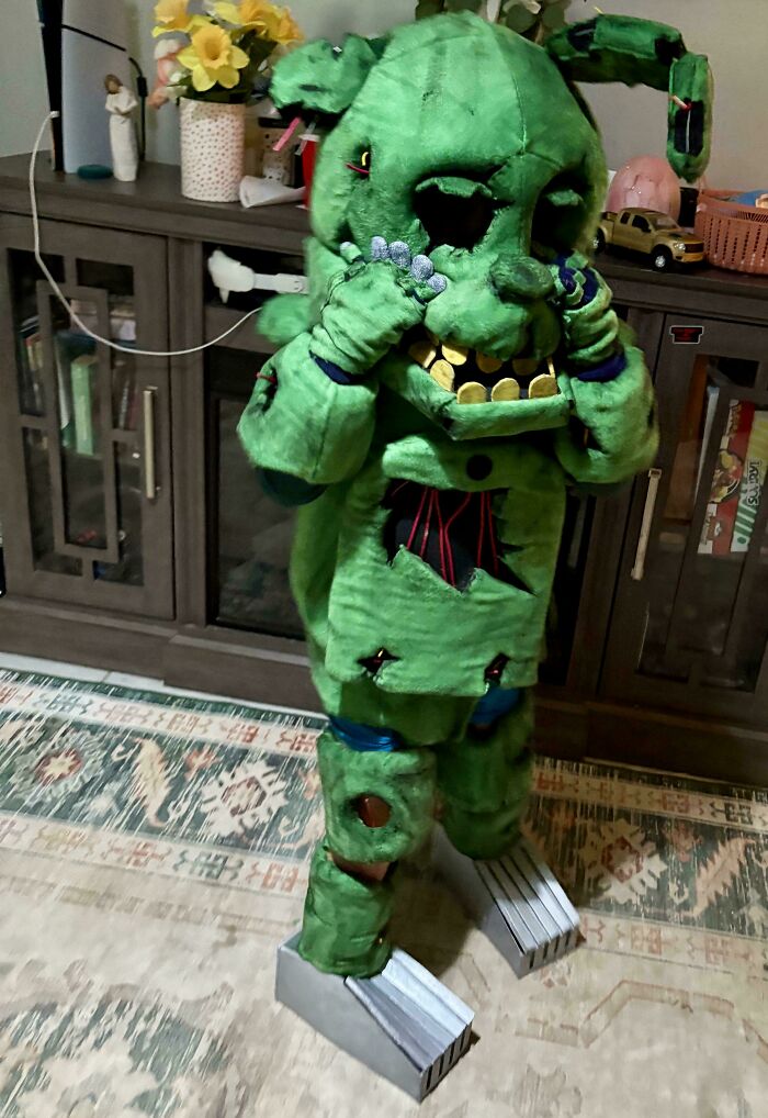 Child wearing an elaborate green animatronic costume indoors, showcasing creative kids' Halloween costume ideas.