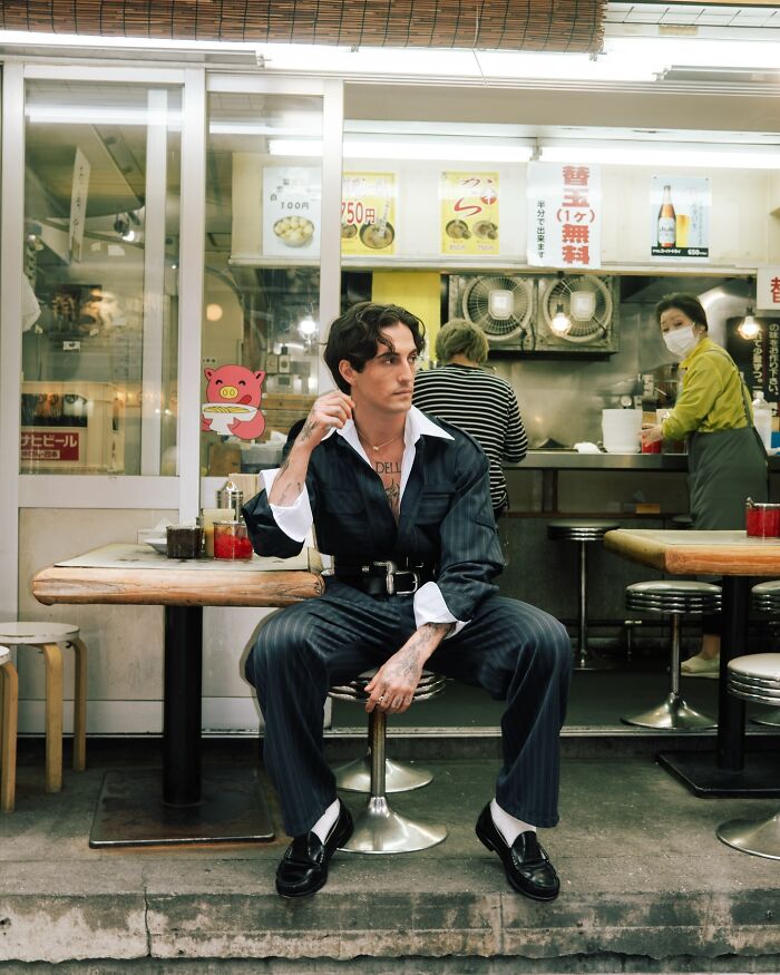 Young man posing confidently outside a casual eatery, embodying style and charm for the most handsome man 2025.