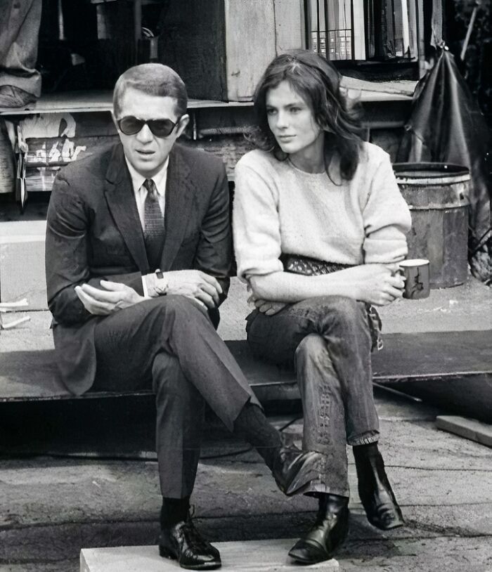 Black and white photo of two people sitting outdoors, representing iconic figures in movie and music industries.