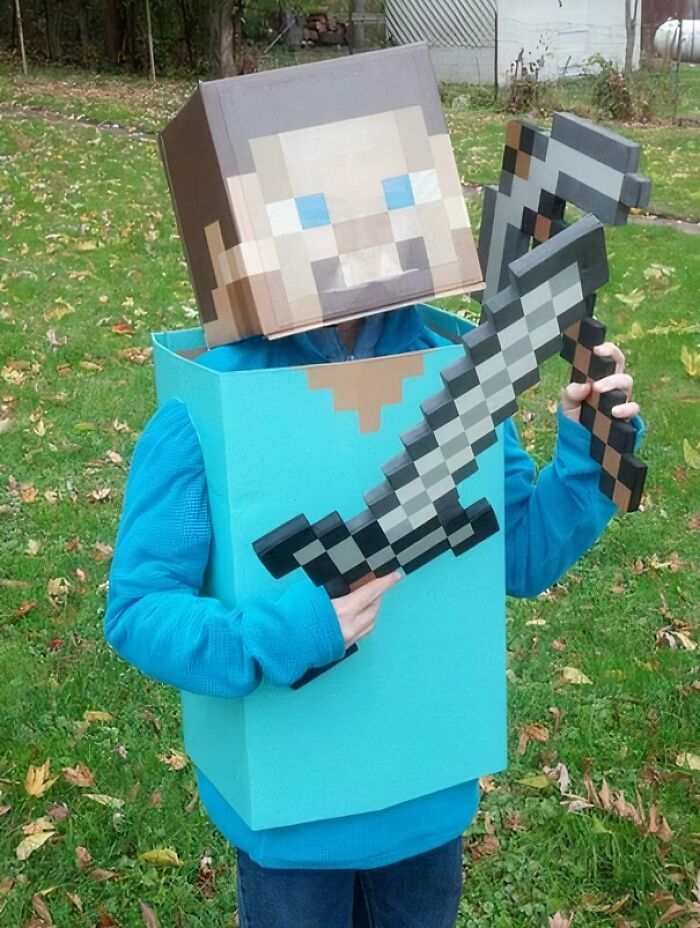Child dressed in an amazing kids' Halloween costume inspired by a pixelated video game character with sword and axe props.