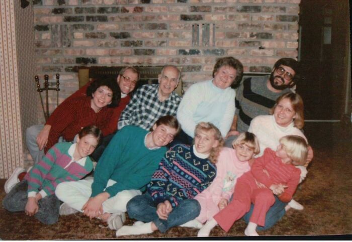 Large family photo with multiple generations laughing and posing awkwardly, showcasing cringed family photos online.