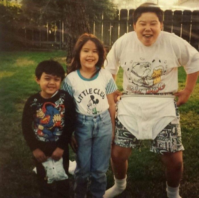 Three kids posing outdoors in humorous family photo, wearing oversized underwear for a funny and cringed family photo moment.
