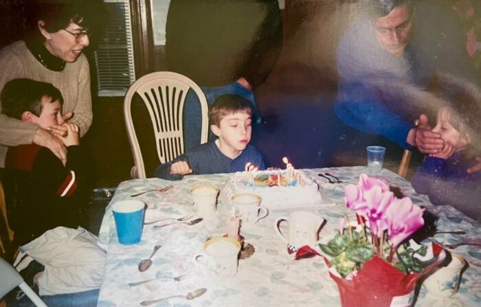 Family birthday photo where kids and adults awkwardly pose, capturing a cringed moment families often share online.