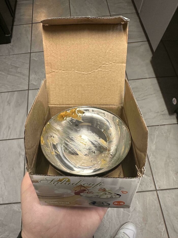 Opened cardboard box showing a scratched and dirty metal salad cup, illustrating careless online shopping backfired.