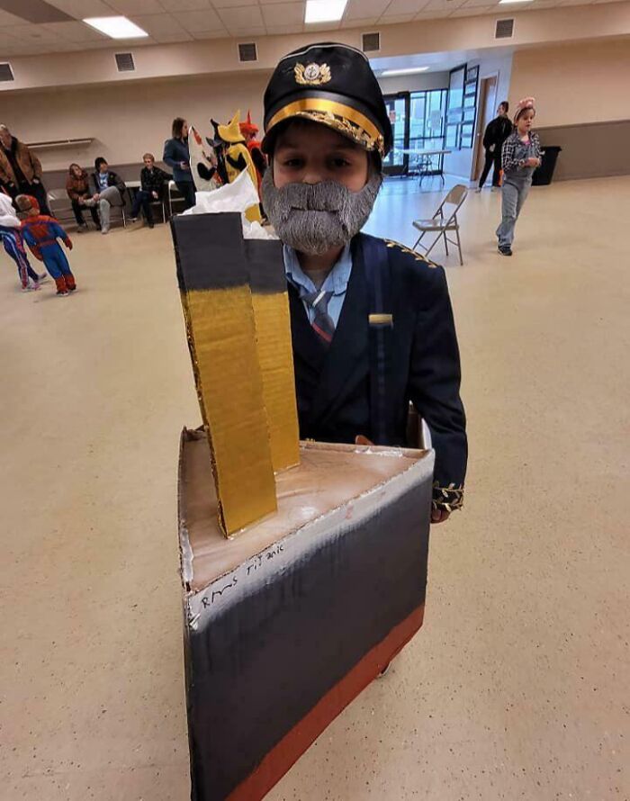 Child dressed in captain costume with a cardboard ship for creative kids Halloween costume ideas that worked like magic.