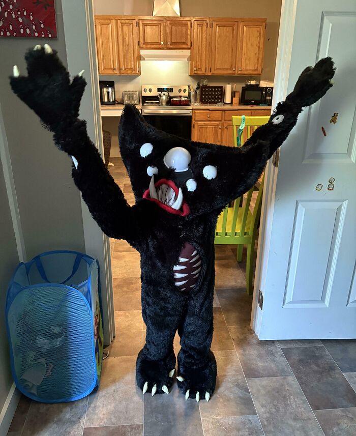 Child dressed in an amazing kids Halloween costume with black furry monster design in a home setting