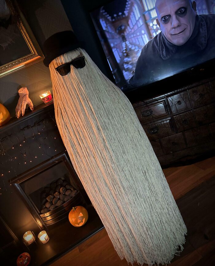 Kids' Halloween costume idea featuring a ghost with long strands, sunglasses, and a top hat in a spooky room setting.