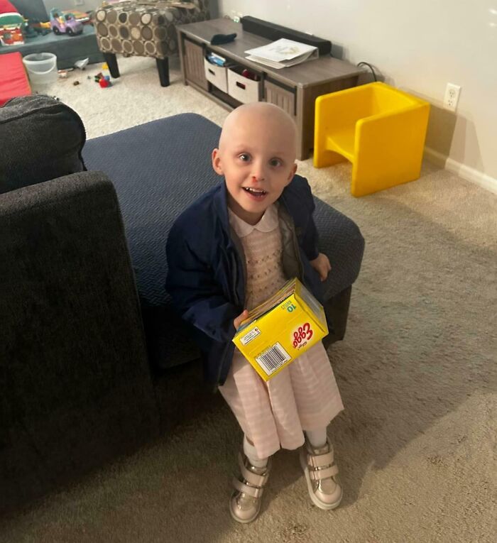 Child smiling indoors wearing a dress and jacket holding a box, one of the amazing kids Halloween costume ideas that worked.