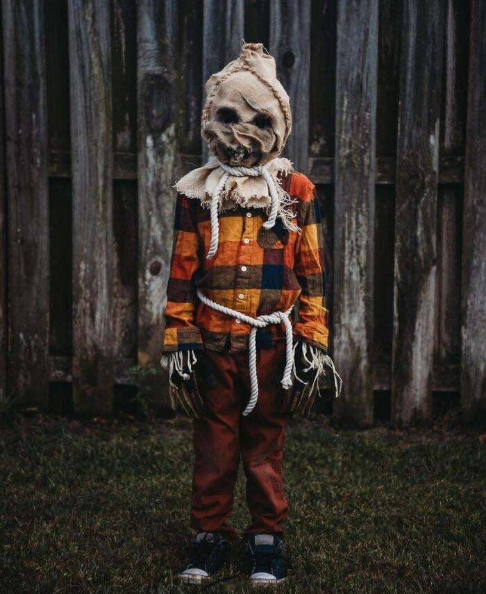 Child in scary homemade Halloween costume with a burlap mask and plaid shirt posing outdoors for kids' Halloween costume ideas.