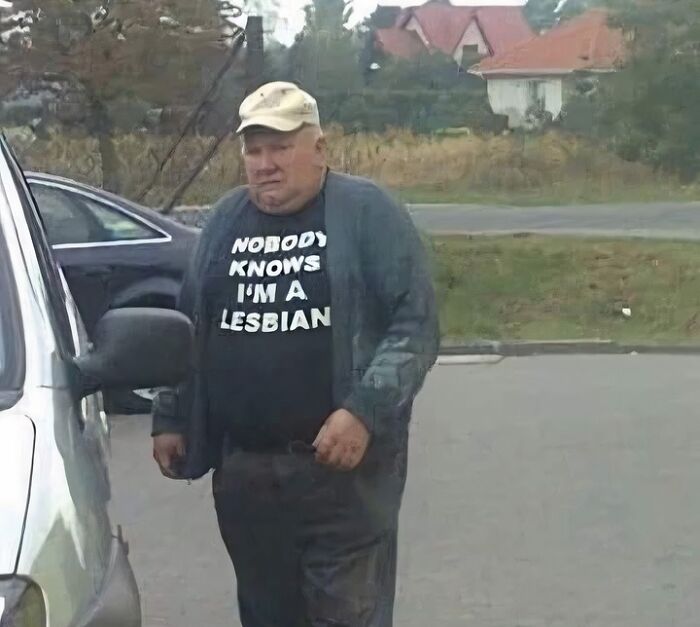 Man wearing a funny T-shirt in an outdoor parking lot, captured in a hilarious out of context occult pleasures moment