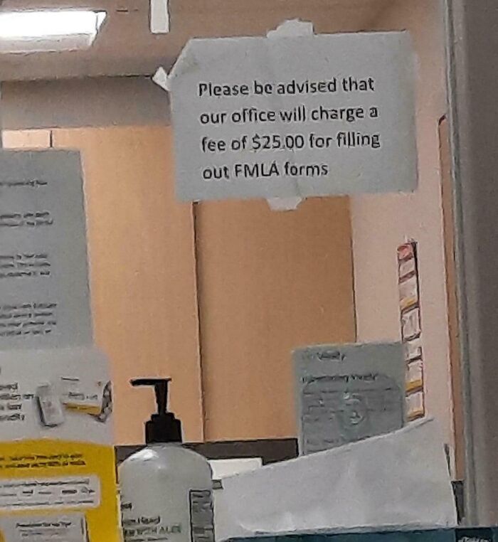 Sign on office wall stating a $25 fee for filling out FMLA forms, highlighting harsh realities of American healthcare.