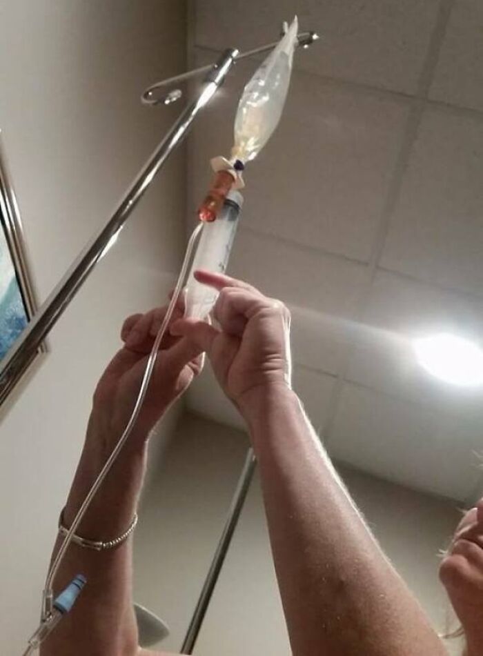 Hands adjusting an IV drip in a clinical room highlighting harsh realities of American healthcare system.