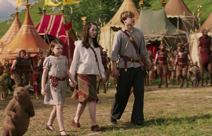 Three children walking in front of colorful tents in a famous mysterious and magical imaginary world scene