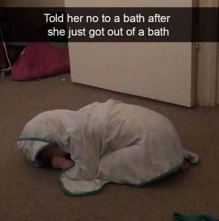 Child wrapped in a towel lying on the floor with meme text about refusing a second bath after just finishing one.