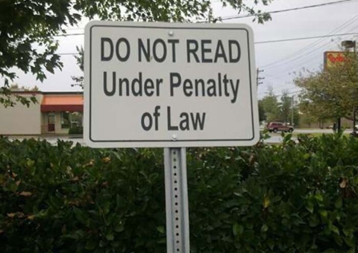 Road sign with confusing message saying do not read under penalty of law, confusing drivers and pedestrians.